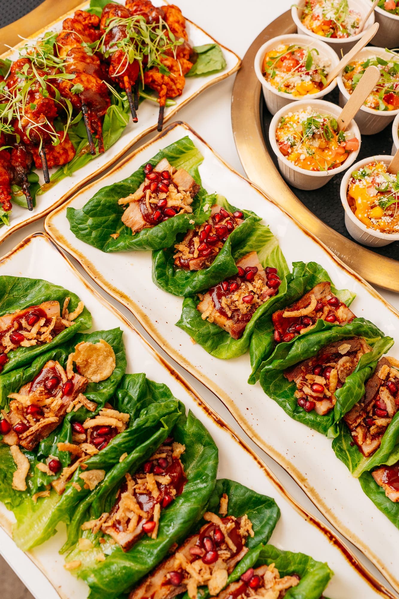 Pork belly lettuce wraps with pomegranate, lined up on a platter