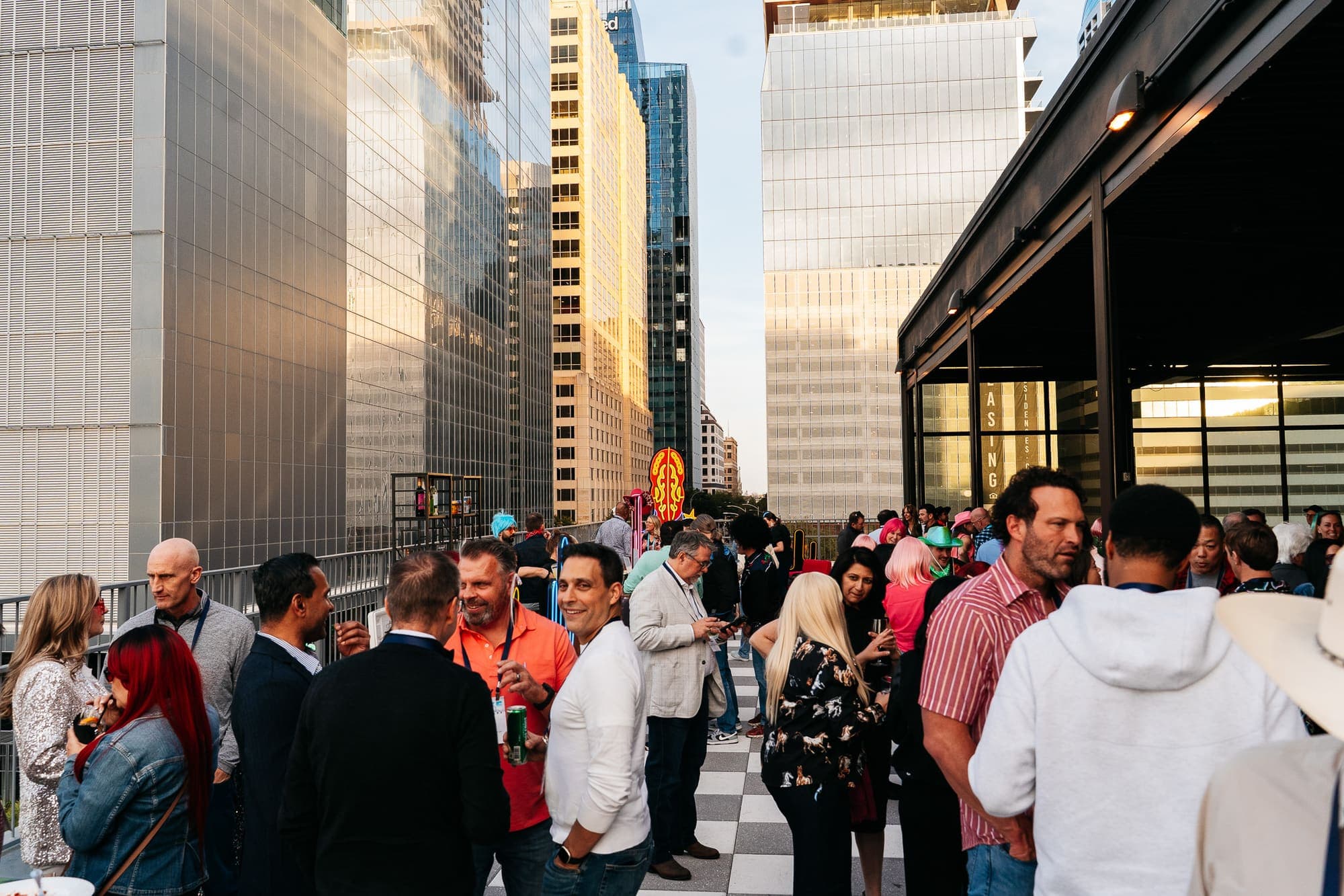 A company crowd mingling on a downtown rooftop at golden hour