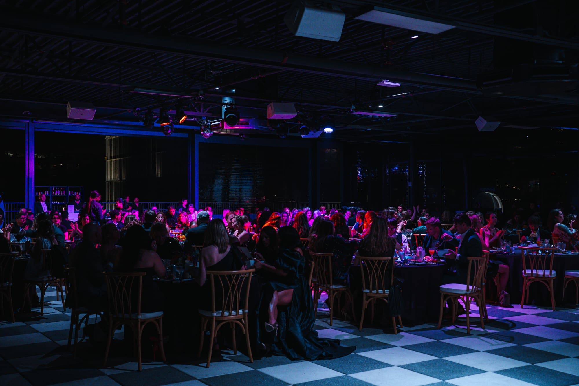 A seated gala dinner under stage lighting